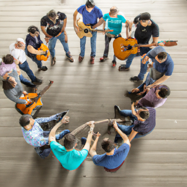 Zehn Personen stehen im Kreis, spielen akustische Gitarren und halten einen Stock.