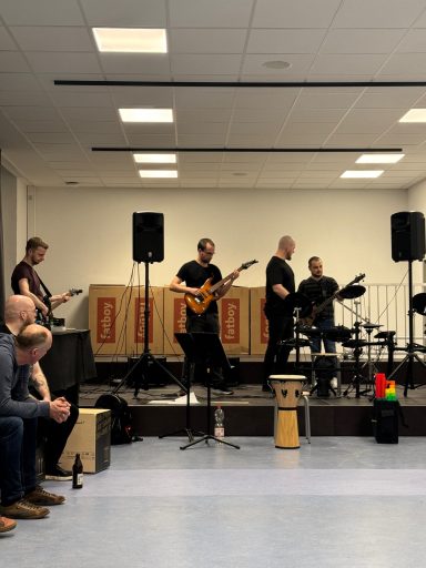 Eine Band spielt live auf der Bühne, Zuschauer sitzen davor und genießen die Musik.